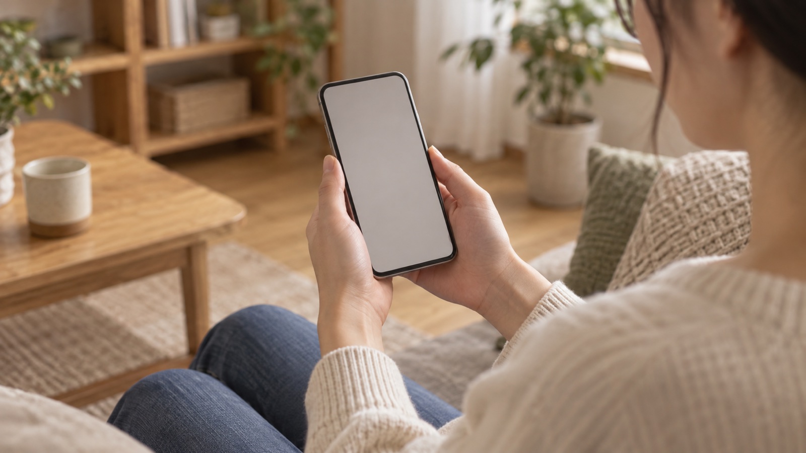 自宅で信用情報について調べるイメージ。リビングでスマートフォンを手にする人の手元